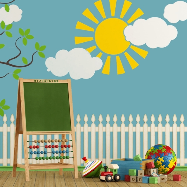 ESPACES_ENFANTS-Photo_640x640-Pièce_enfant_avec_aire_de_jeux_comprenant_tableau_jouets_colorés_dans_décor_extérieur_avec_cloture_arbre_gros_soleil_jaune_ciel_bleu_nuages_blancs