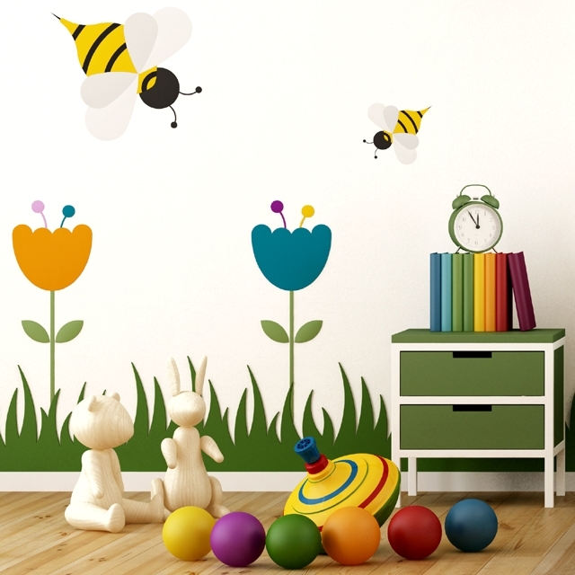 ESPACES_ENFANTS_Photo_640x640_Pièce_enfant_mur_blanc_décorée_avec_herbe_verte_grosses_fleurs_abeilles_meuble_et_jouets_colorés
