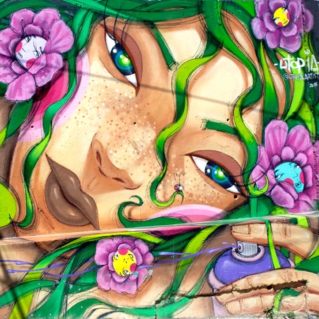PEINTURE_MURALE_Photographie_640X640_cadrée_de_peinture_murale_extérieure_avec_jeune_fille_aux_cheveux_verts_et_fleurs_rose-violet